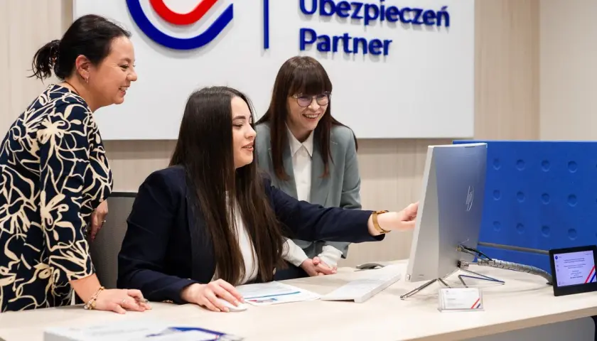 Trzy kobiety przy biurku patrzą na monitor komputera.
