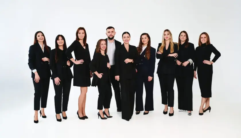Grupa profesjonalistów w czarnych garniturach i sukienkach na białym tle.