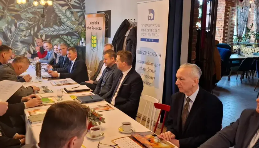 Ludzie siedzący przy stole podczas spotkania, na ścianie banery "Lubelska Izba Rolnicza" i "TUW Ubezpieczenia".